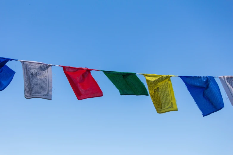 several colorful flags are hanging under a blue sky