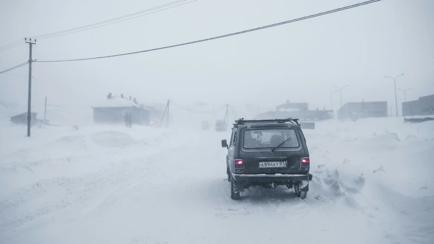 a small suv driving through deep snow on the street