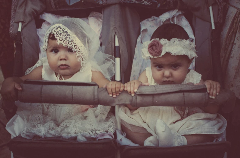 two little children with fancy head coverings in a stroller