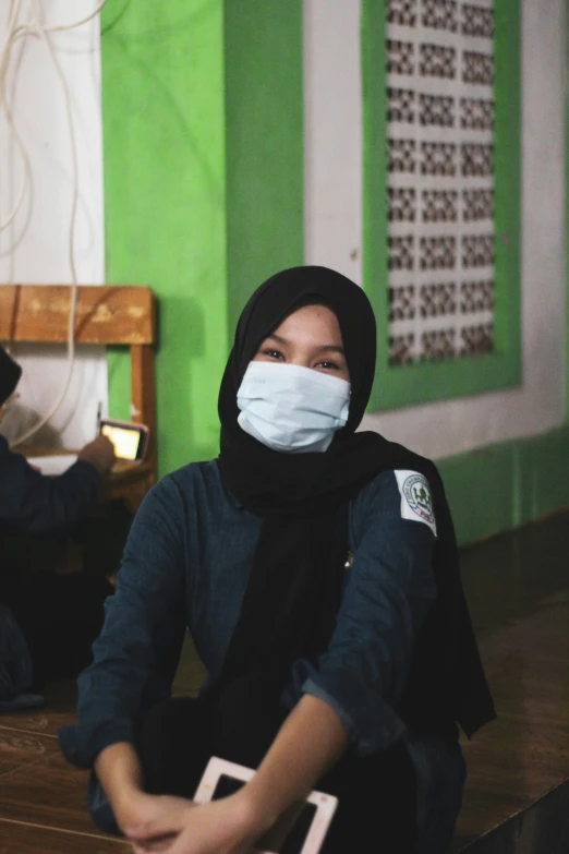 a young woman wearing a mask sits at a table