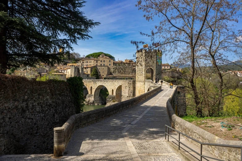 a cobblestone street passing an old city near a rock wall