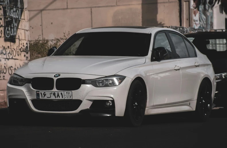 a white bmw in a parking lot next to a wall