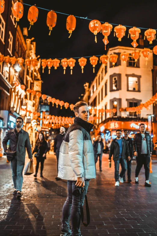 people are walking in an alley with lanterns hanging from the ceiling