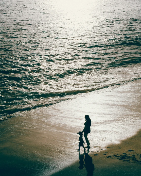 a mother and baby walking along the beach