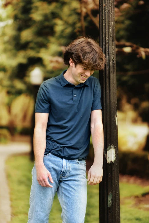 a young man leaning against the edge of a sign post