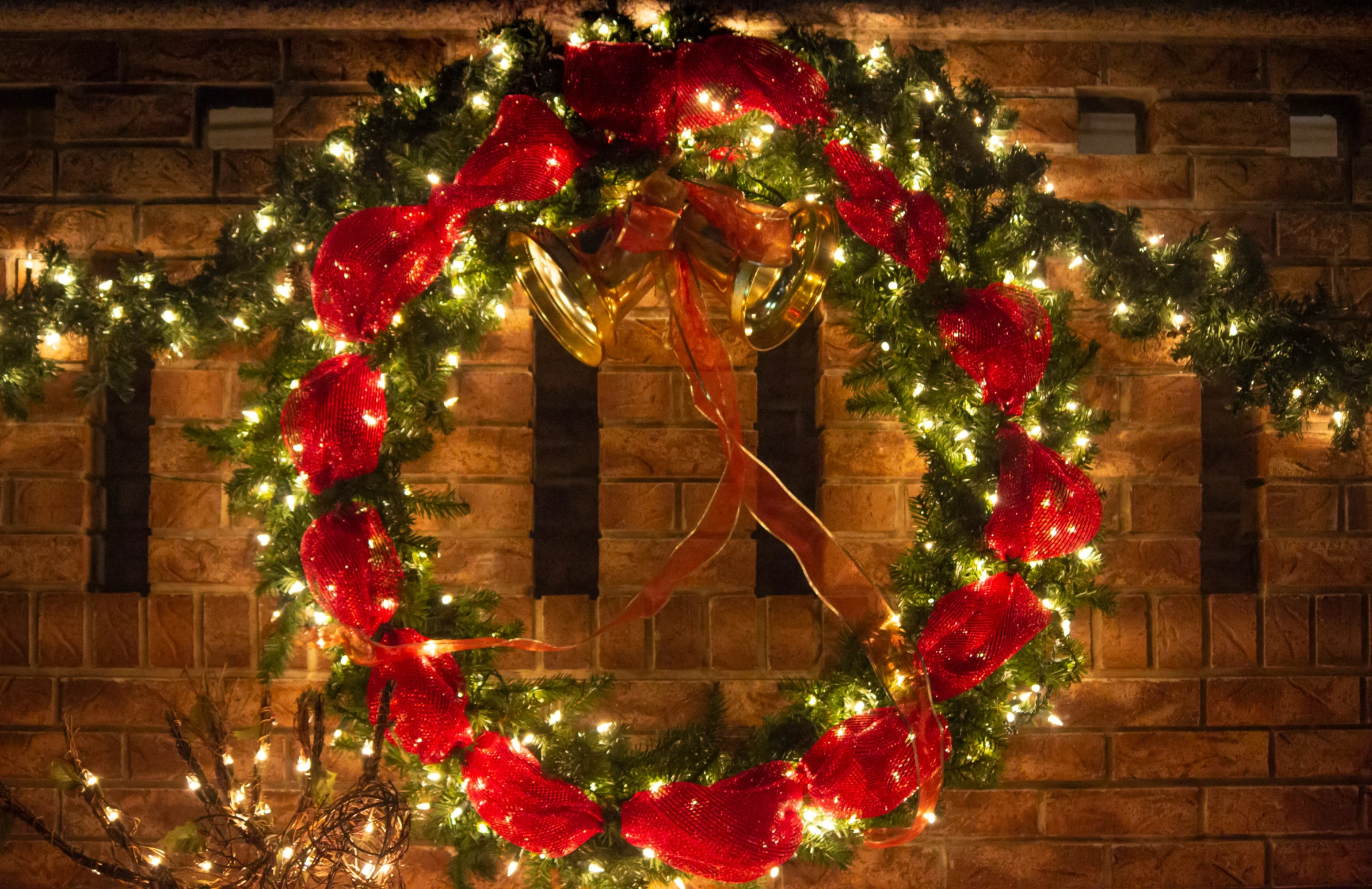 a holiday wreath sits next to a brick wall