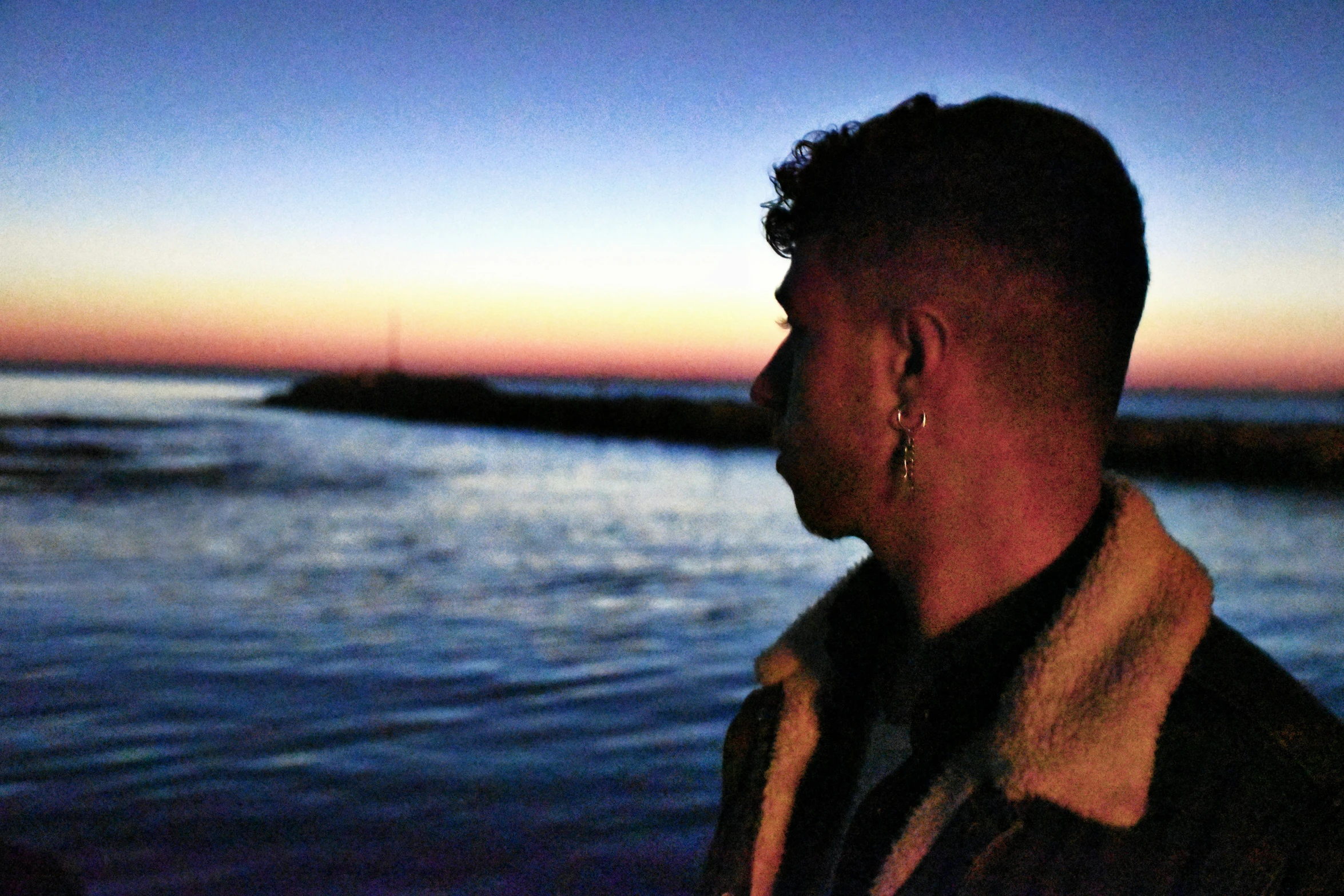 a man staring at the water from a beach