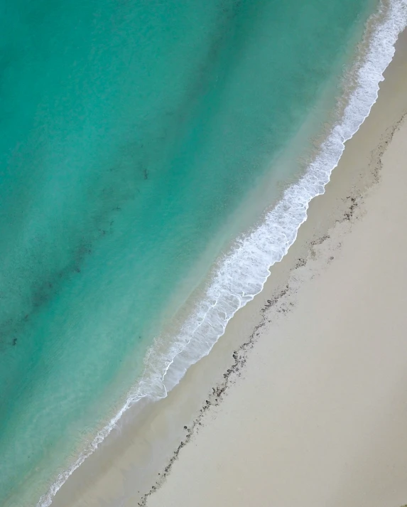 an overhead view of the beach and ocean with white sand