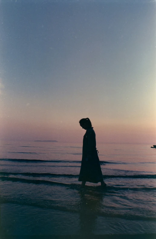 woman walking along the ocean while looking to horizon