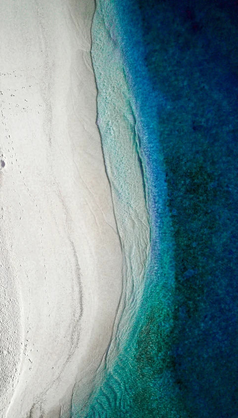 an aerial view of a sandy beach with blue water