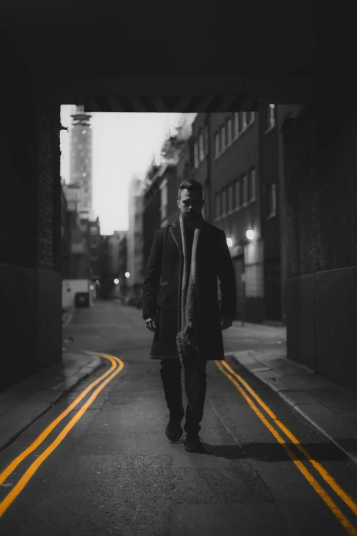 man in a coat walking down a street at night