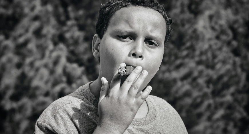 man in gray shirt taking a bite out of a pastry