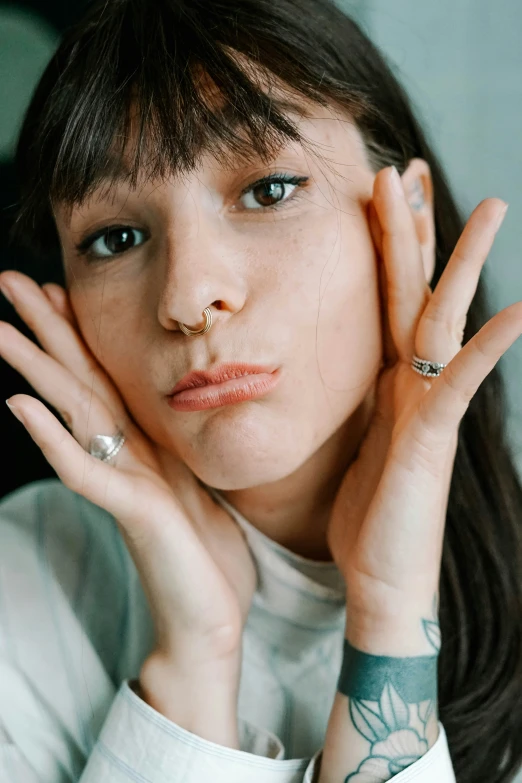 a person wearing a white shirt is holding their hand near their face