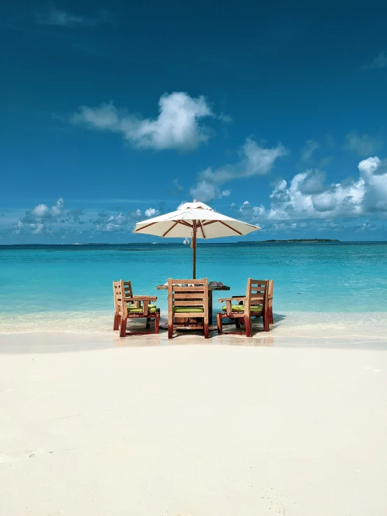 two chairs are set on the beach for a meal