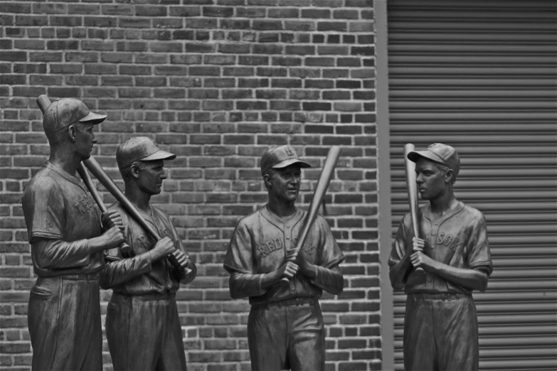 black and white image of a statue with three men holding baseball bats