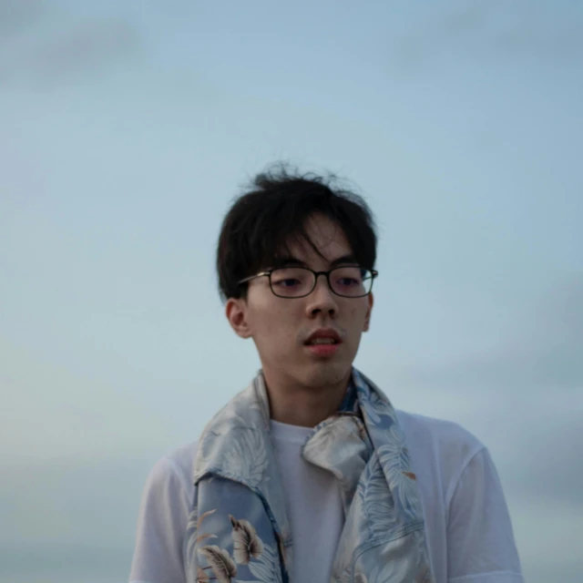 a man with glasses wearing a blue scarf and white shirt