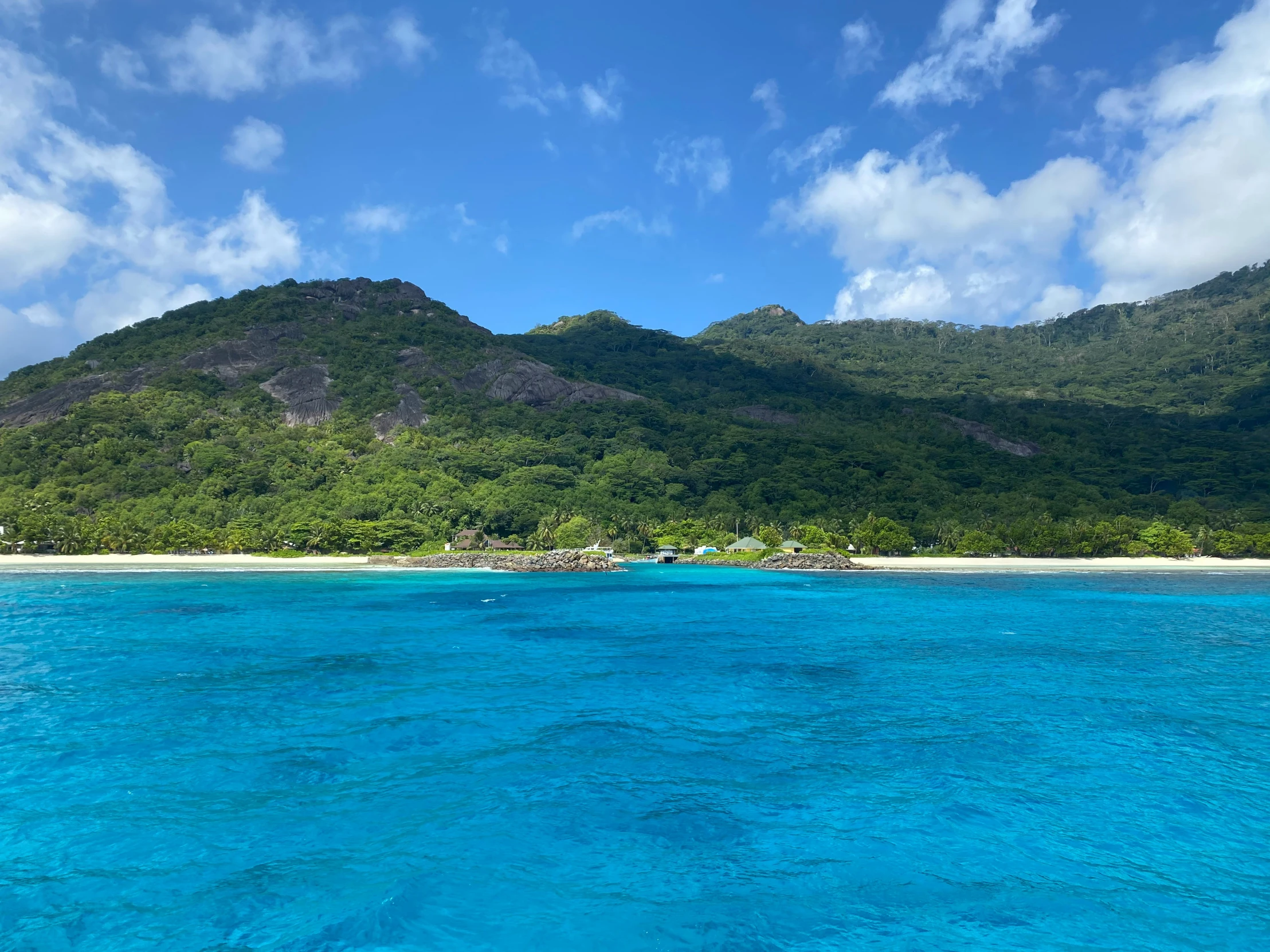 water and hills are next to each other with a blue sky and ocean