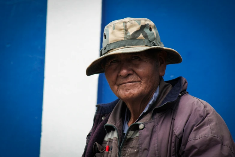 an elderly man in military clothing smiles and stares