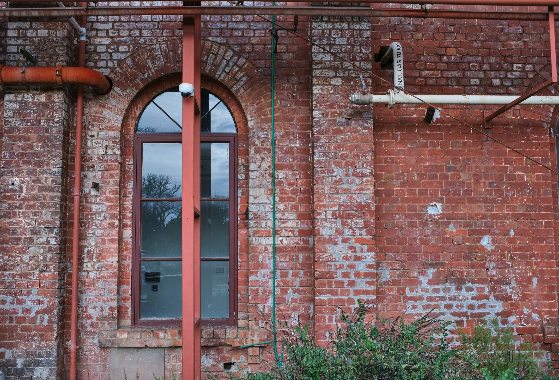 a run down building has two windows and two rusty pipes