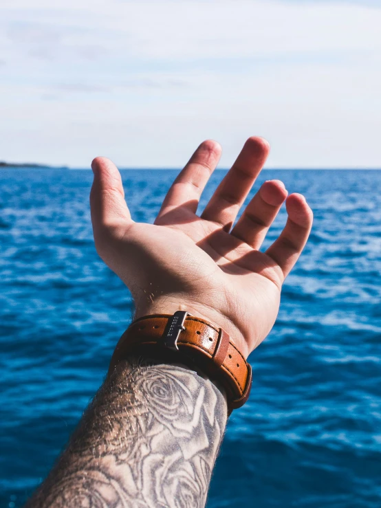 someone holding their hand out in front of a body of water