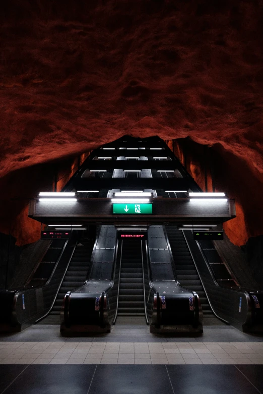 an empty escalator with luggage on the other side and a neon sign reading 6
