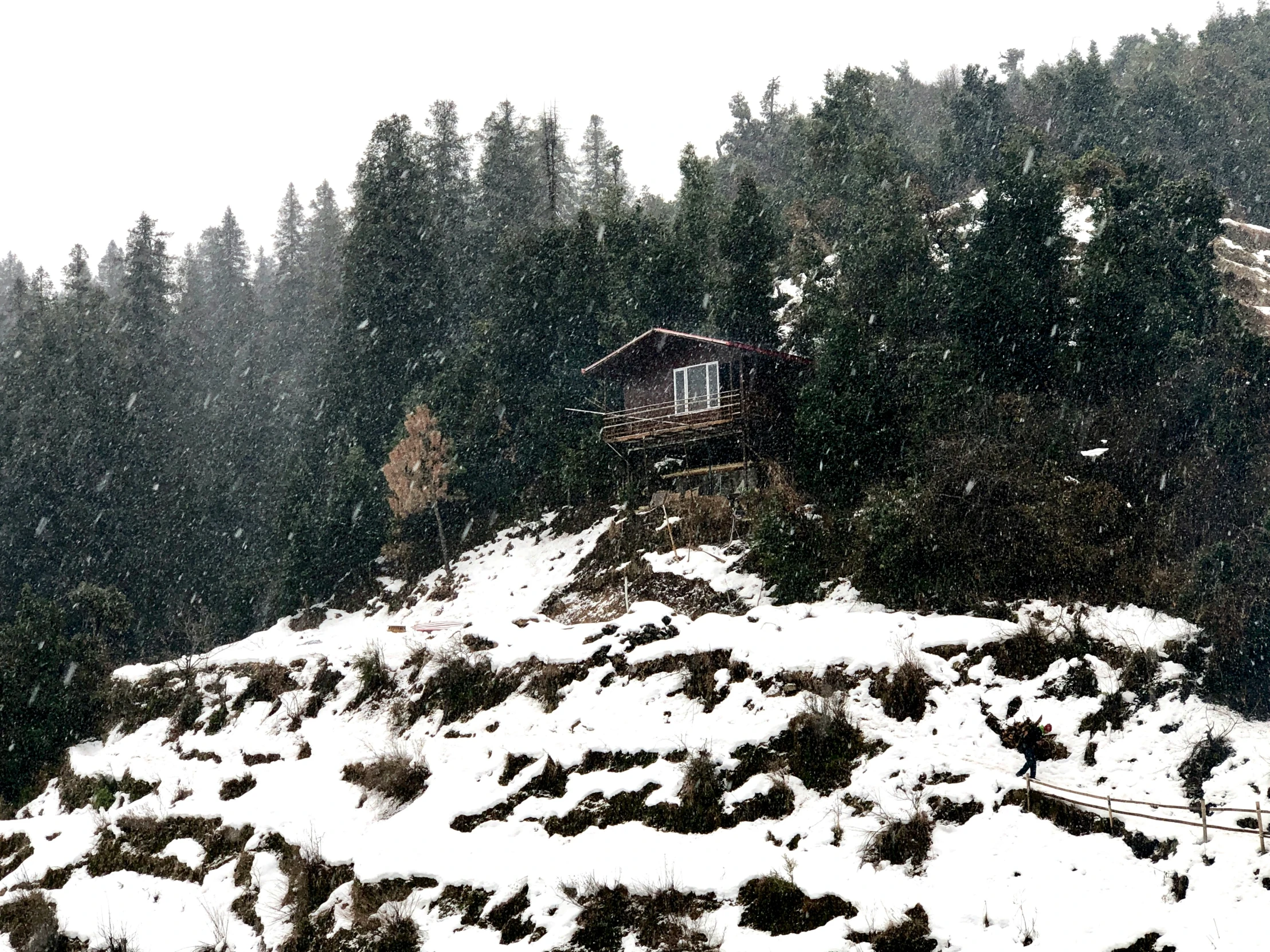 a cabin on top of a snowy mountain is set on top of a hill