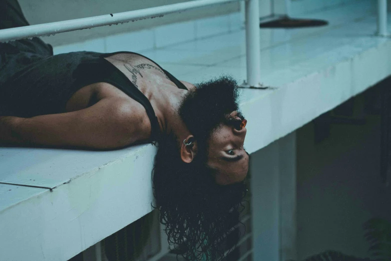 a woman with black make - up and fake hair laying down on top of a roof