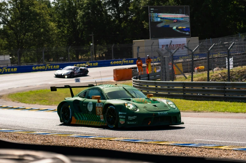 a green racing car on the racetrack in front of another car