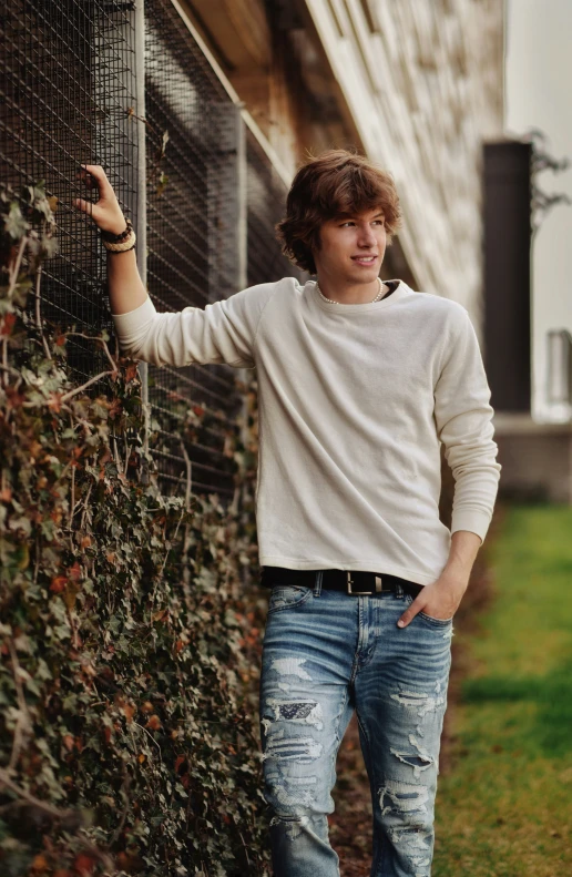 the young man is posing for a po leaning on the fence