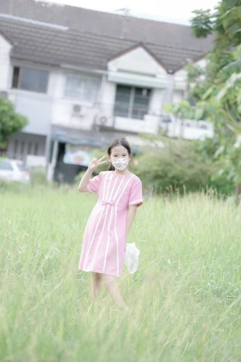 a young child wearing a pink and white dress walks through tall grass