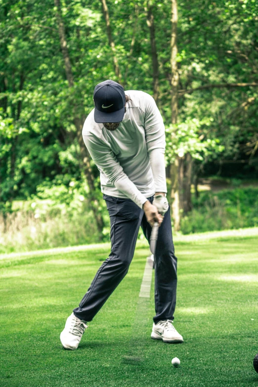 a man holding a golf club on top of a green field