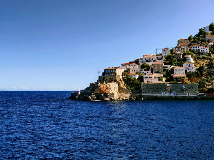 the view from across the ocean looking down at a small town on a cliff