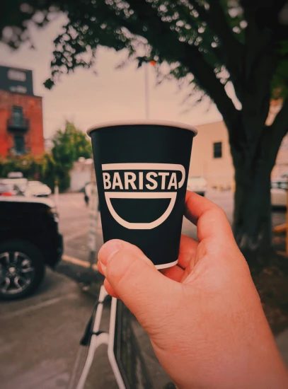 a person holds a black cup with an advertit on it