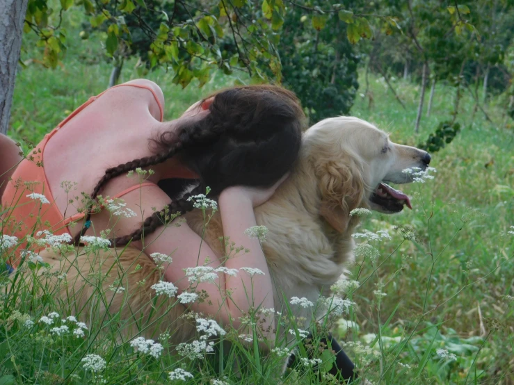 a woman laying on the ground holding onto a dog