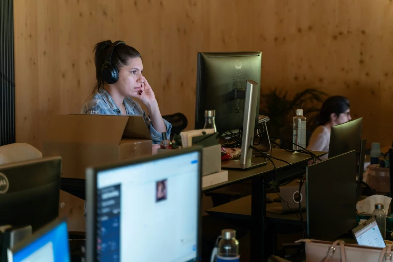 a woman sitting at a desk with two monitors