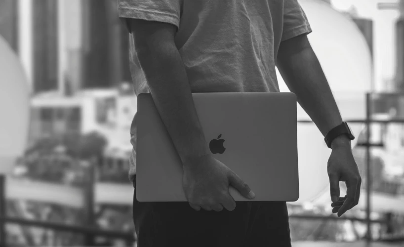 a person is holding an apple laptop in his hand