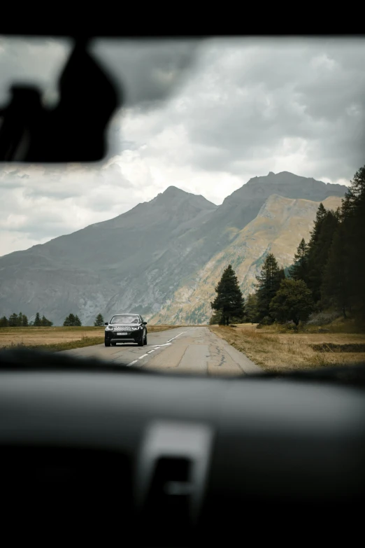 a car driving down the road next to mountains