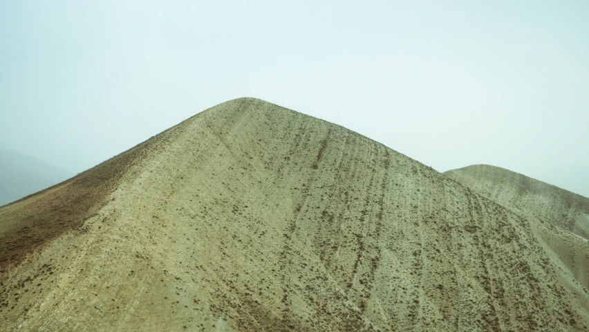 there are many sand dunes and a mountain in the background