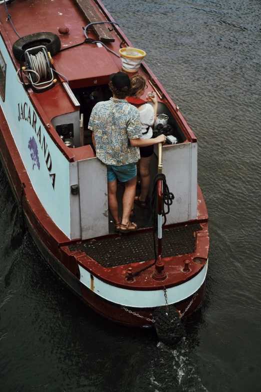 a man and woman standing on the back of a boat