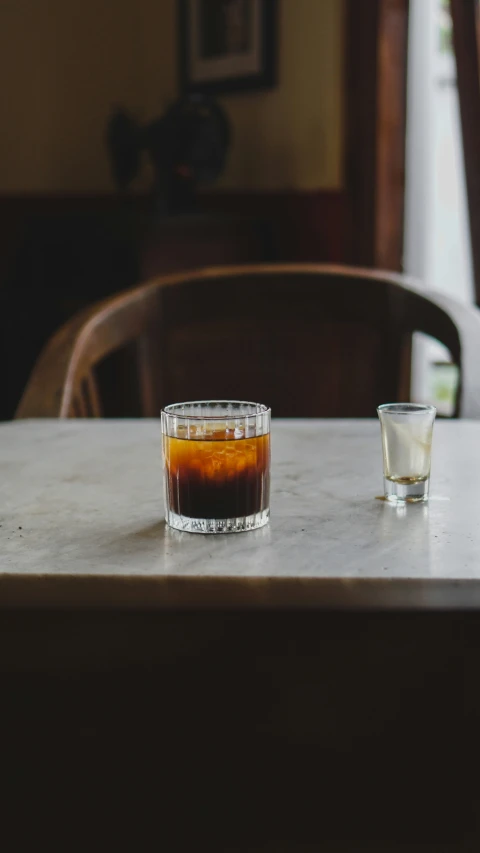 a s glass sitting on top of a table next to an empty cup