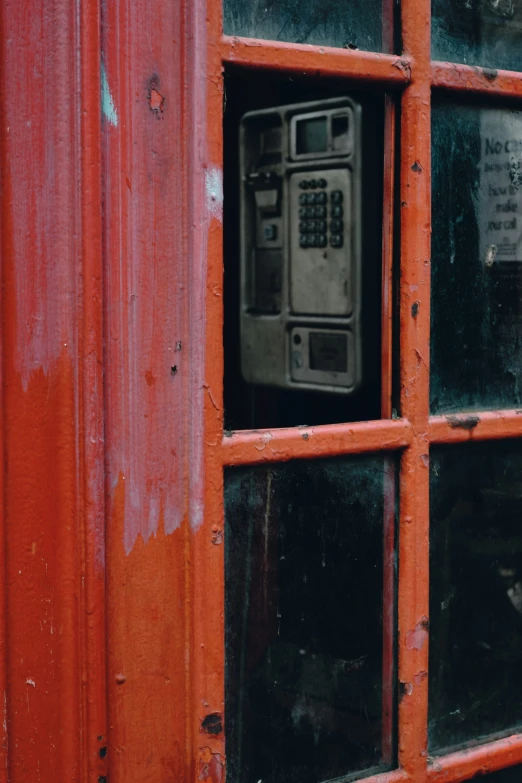 a window view of a telephone inside a small red building