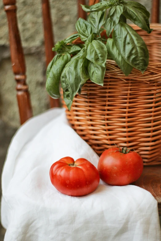 a couple of tomatoes sit on a table next to some leaves