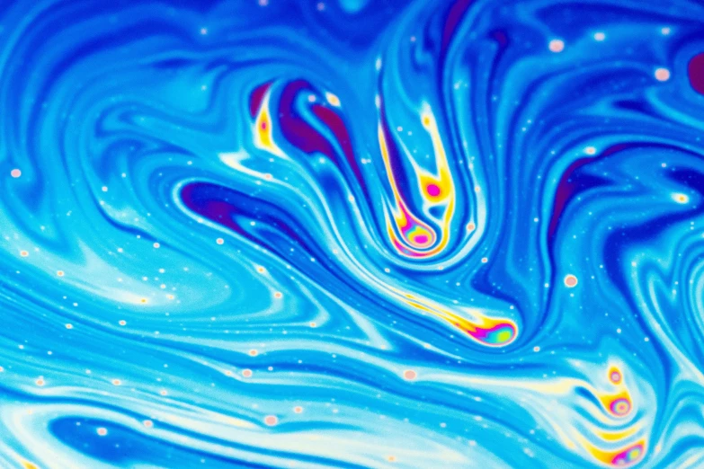 blue and yellow colored fluid liquid pouring out from one substance into another liquid