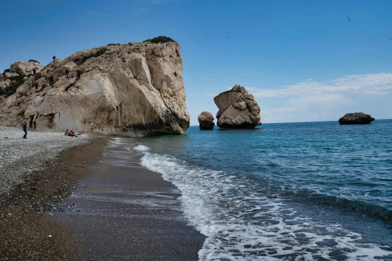 two rocks sticking out of the ocean by a beach