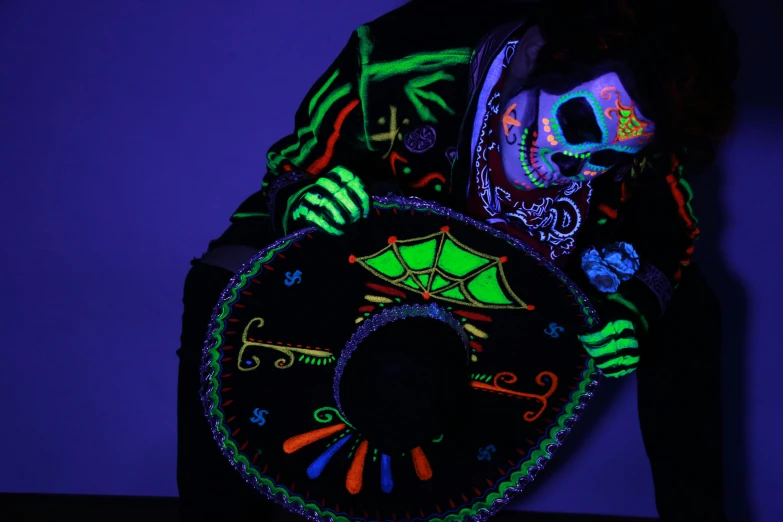 the skeleton with a glow mask is holding up an illuminated clock