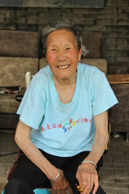 a woman sitting on a chair in a blue t - shirt