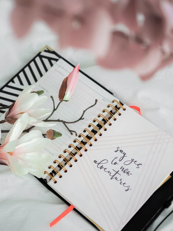 a notepad with writing and white flowers