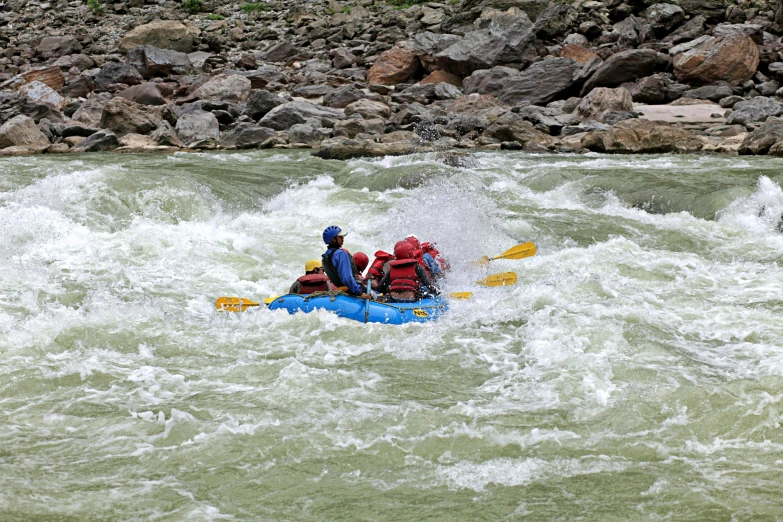 three people white water rafting through some rapids