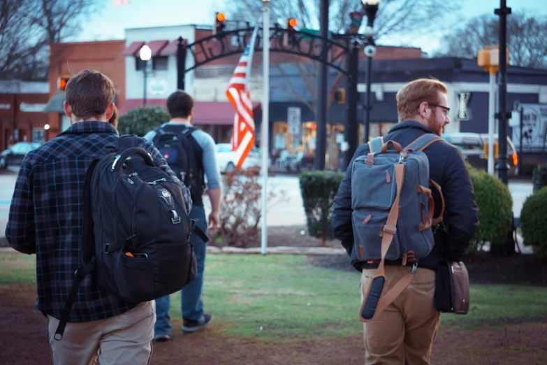 two men who are standing by the street with their back to us