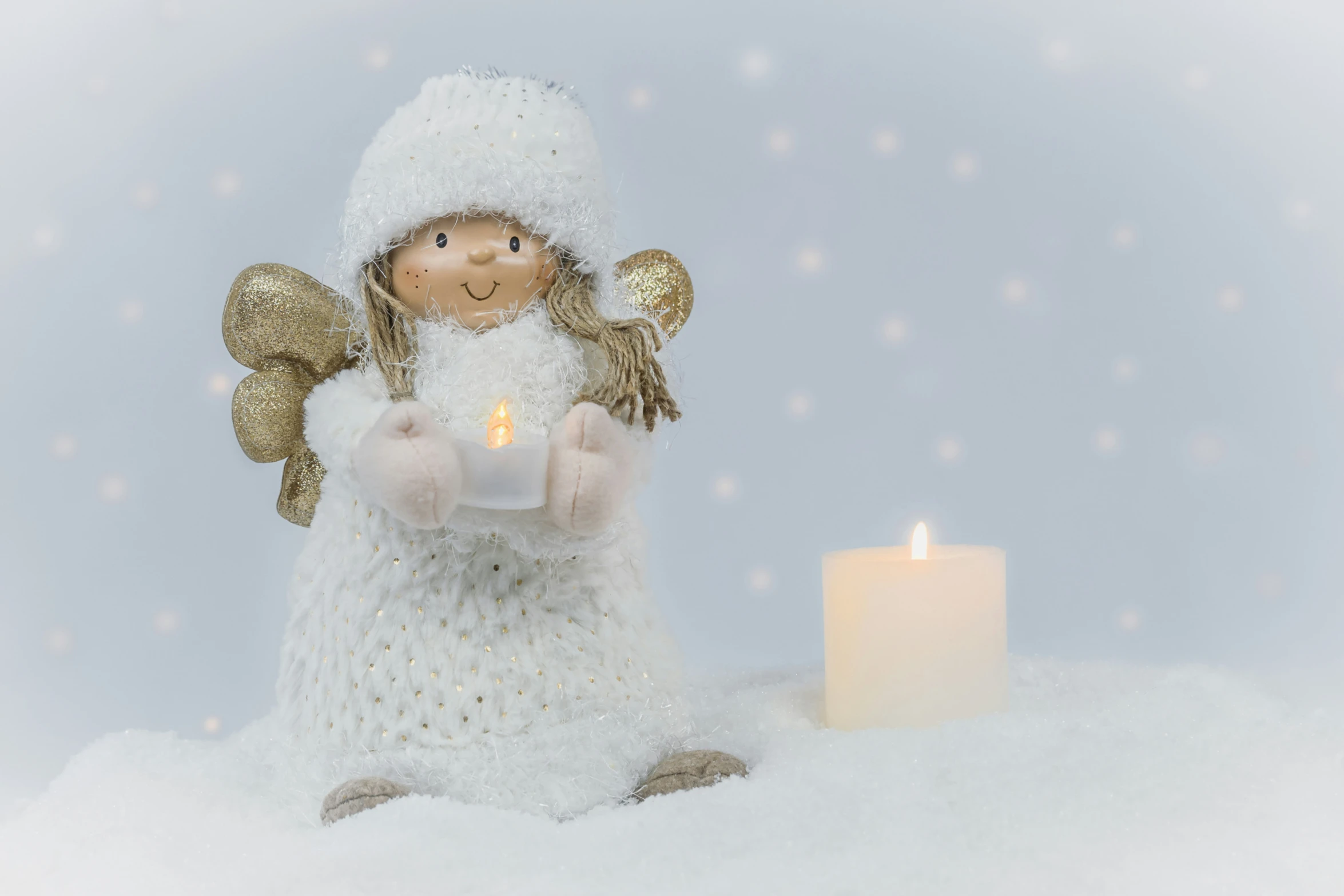 a toy angel holding a candle standing in the snow